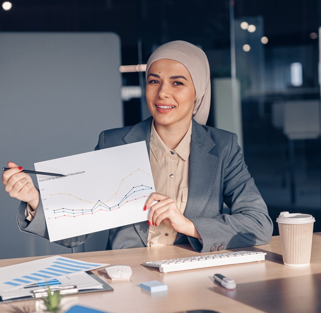 smiling muslim businesswoman in hijab shows a grap amh74w7.jpg